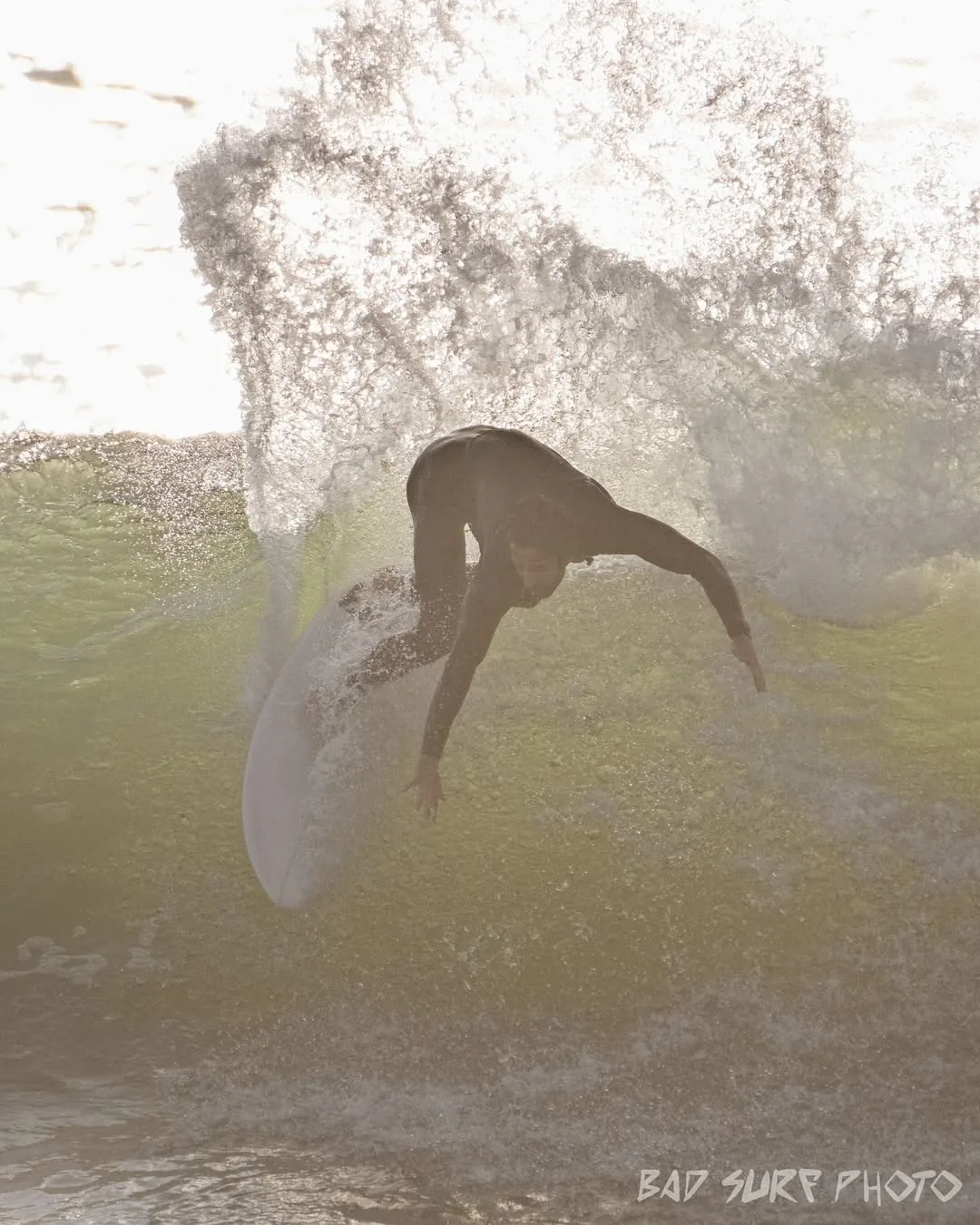 Surfista em contraluz entre spray dourado