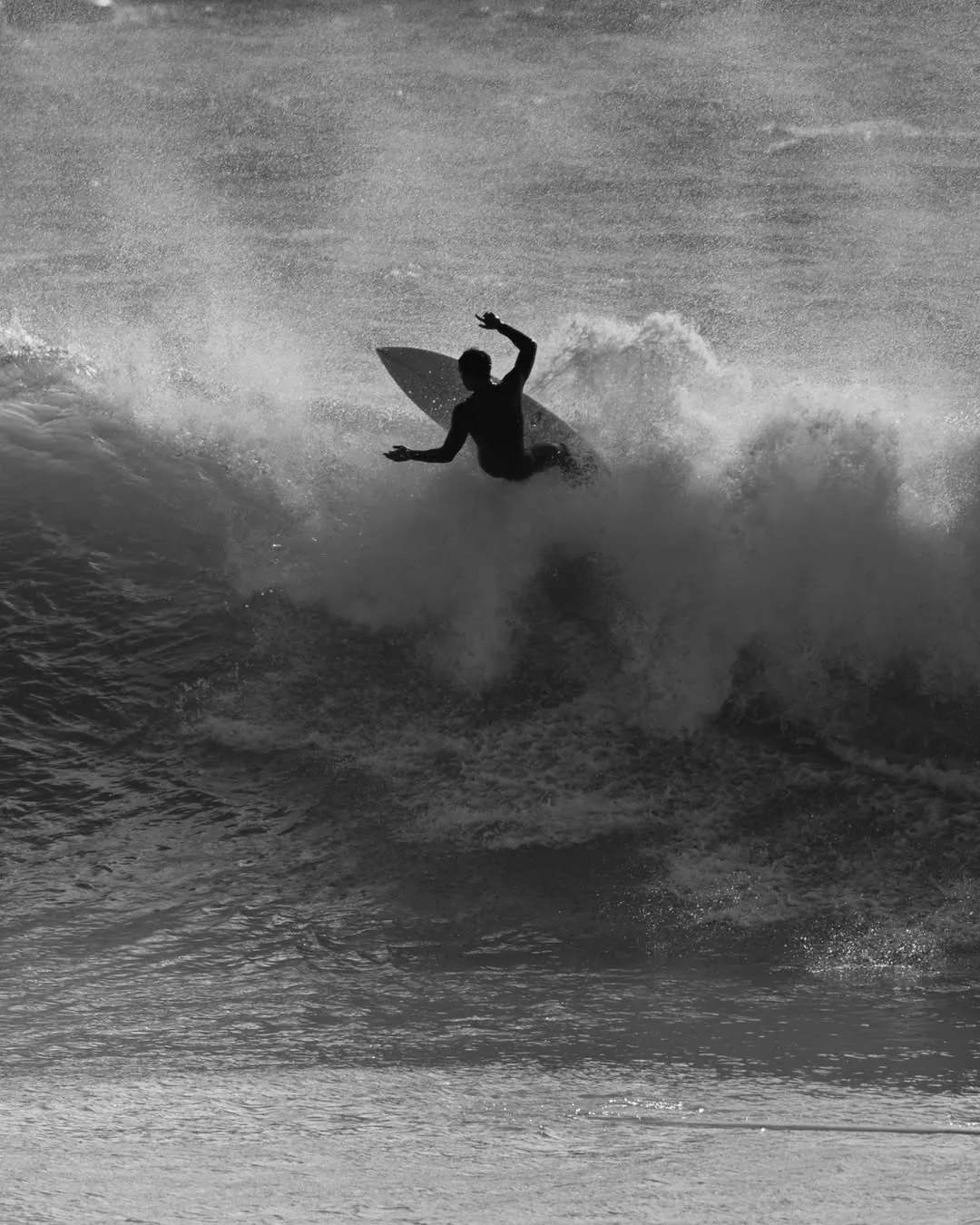 Surfista a rasgar a onda, a preto e branco
